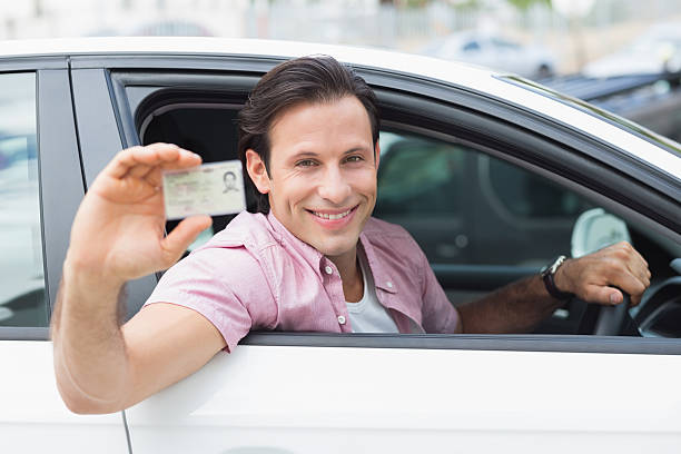 istock Man smiling and holding his driving license 474538042