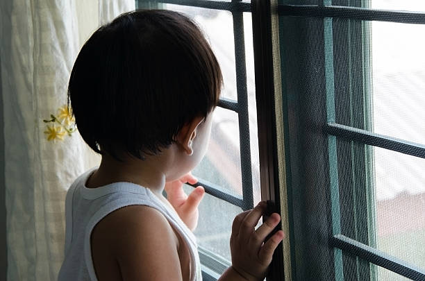 istock boy standing near the window 474541434