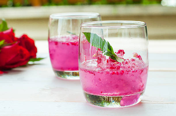 istock Pink Cocktail with fresh rose petals on wooden table 474544098