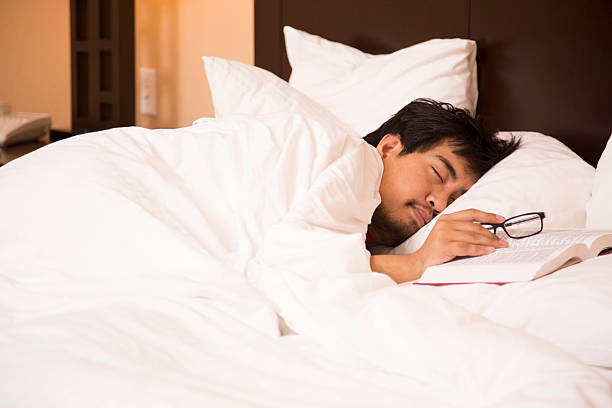 istock Business man fell asleep while reading book. Hotel room bed. 474551084
