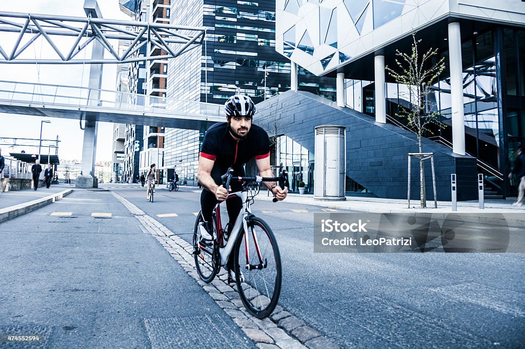 Commuter cycling fast at work in the morning In the early morning the city is populated by sportive commuters wearing backpacks and going at work in the business district of the town. 2015 Stock Photo