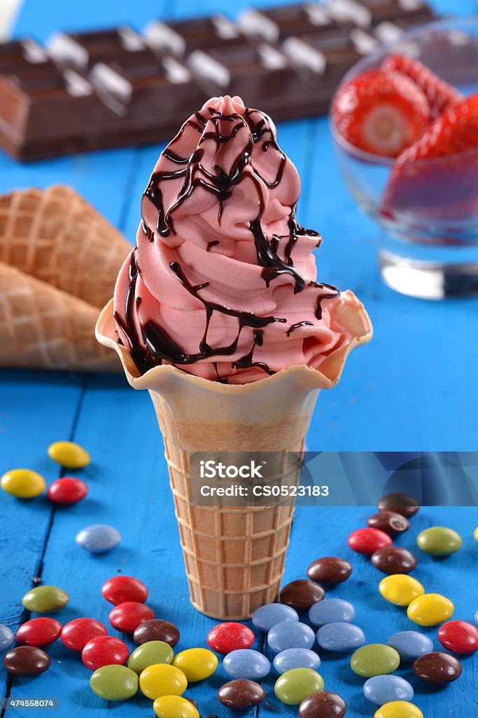 The ice cream cone at party. Strawberry ice cream cup and chocolate syrup on party ambient. Strawberry sundae icecream and ingredients. 2015 Stock Photo