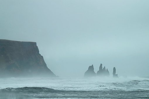 Towering basalt sea stacks situated under the mountain Reynisfjall near the village Vík í Mýrdal, southern Iceland.