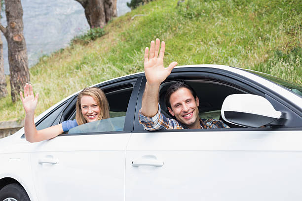 istock Young couple smiling and waving 474563630