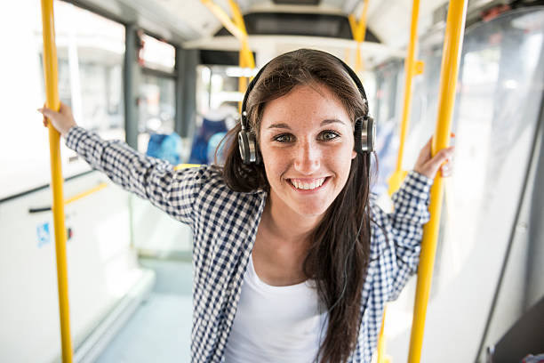 Felice giovane donna con auricolare telefono sull'autobus - foto stock