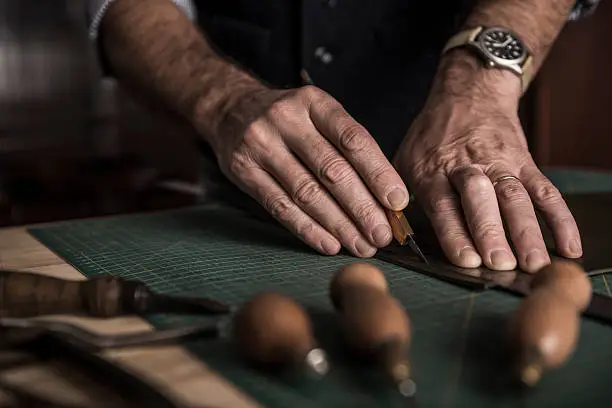 Close up shoot of an artisan working with leather in his laboratory.