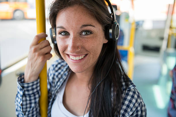 Young happy woman with ear phone on the bus stock photo