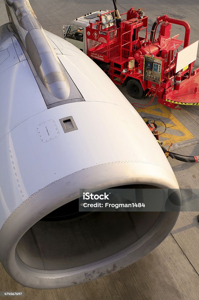 Refuling Engine A refueling truck dwarfed by the engine of the aircraft it is refueling. Aerospace Industry Stock Photo