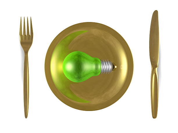 Green light bulb, golden plate, fork and knife. Top view