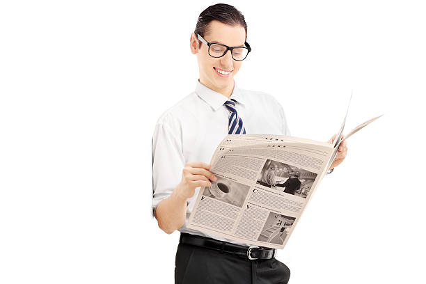 istock Smiling businessman leaning against wall and reading a newspaper 474572877