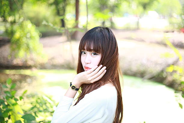 A lovely asian woman in a park’ grassplot.