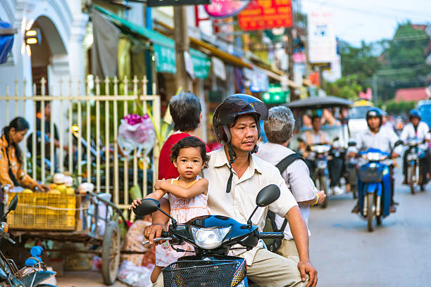 Siem Reap, Cambodia - November 27, 2012: Commuter and a Family riding a motorcycle. Busy road during rush hour.