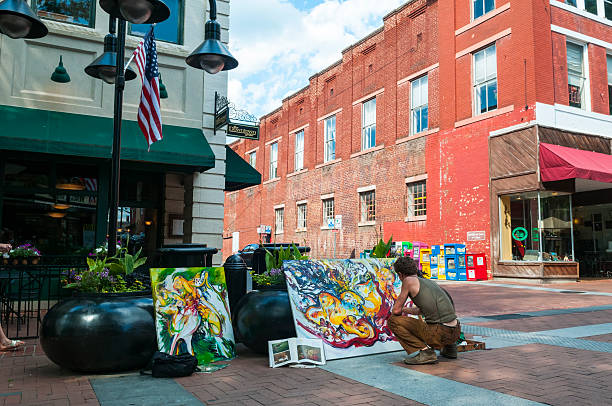 Charlottesville, Virginia - June 7, 2012: A man paints on a canvas on a summer day at the Downtown Mall, a pedestrian area in the center of Charlottesville, Virginia