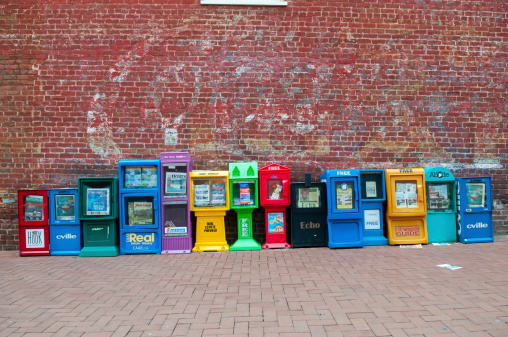 Charlottesville, Virginia, USA - June 7, 2012: A line of dispensers offering mostly apartment and real estate newspapers and ads in Charlottesville, VA