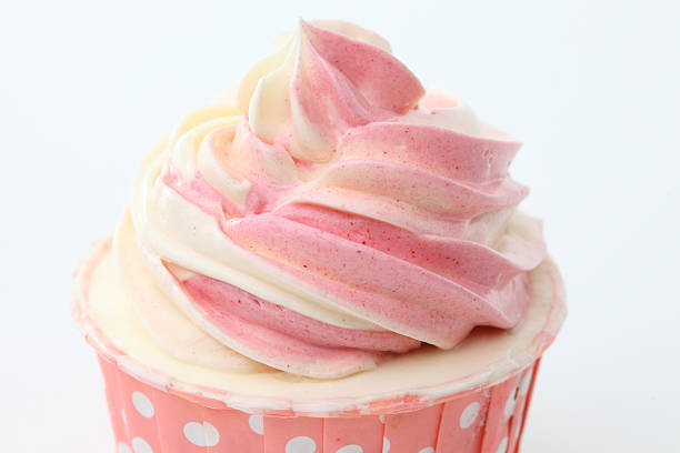 Cupcake with swirls of creamy strawberry frosting on white background Macro