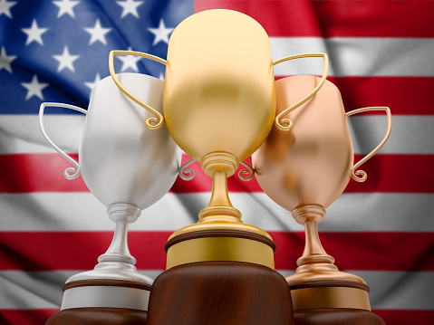 Sport Background with 3 Trophy Cups and unfocused USA Flag on the background