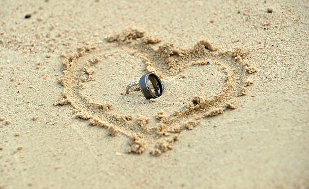 obrączki leżący na piasku w kształt serca - beach love heart shape two objects zdjęcia i obrazy z banku zdjęć