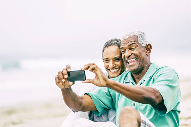 istock Senior couple having fun with smart phone on beach 474586196