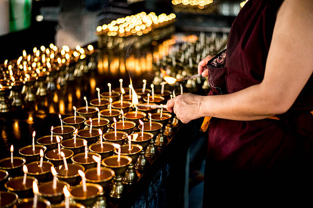 monk lighting prayer lamp on buddha purnima - vesak day 個照片及圖片檔