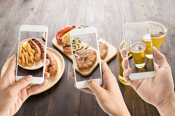 friends using smartphones to take photos of food. friends using smartphones to take photos of sausage and pork chop and beer. barbecue grill photos stock pictures, royalty-free photos & images