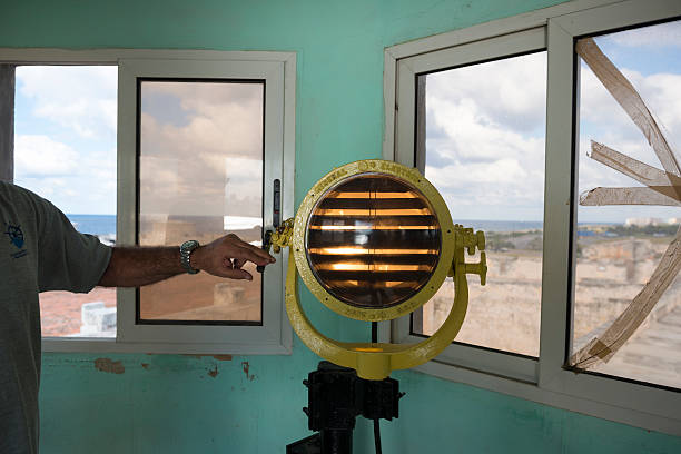 General Electric naval signal lamp in Havana, Cuba Havana, Cuba - December 17, 2014: A man illustrates how to send a Morse code message using a naval signal lamp in Havana, Cuba. This one, located at the harbor master building at the entrance to Havana Harbor, was manufactured by General Electric. havana harbor photos stock pictures, royalty-free photos & images