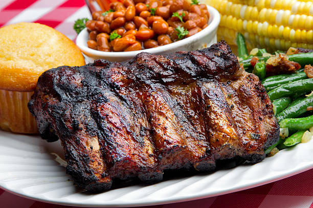Two pieces of the raw pork ribs on the white dish on the rustic table, top view