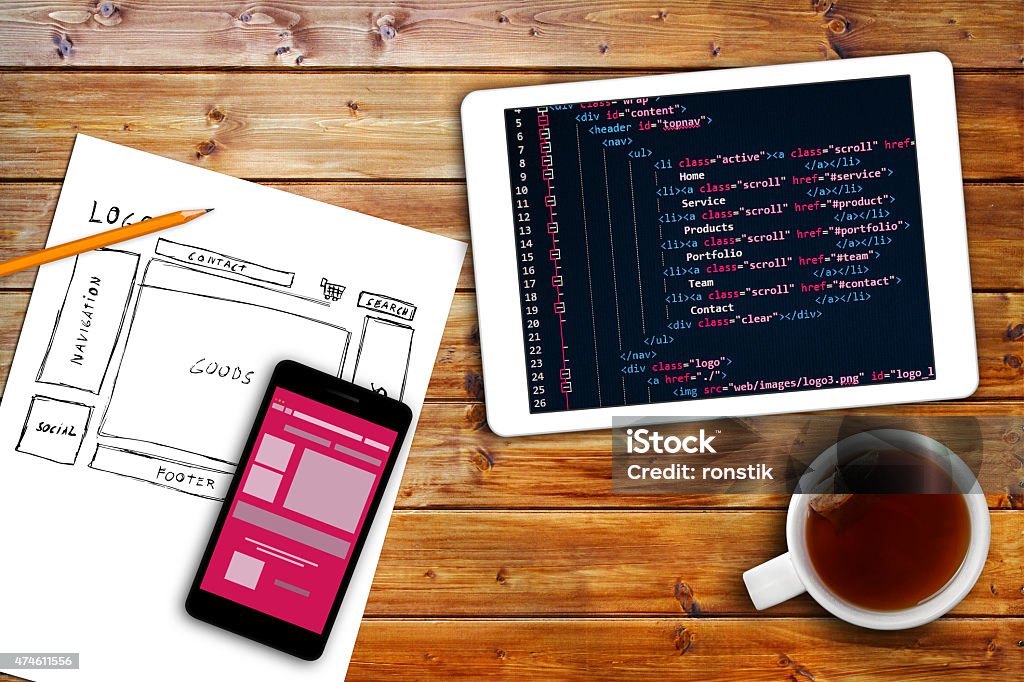 website wireframe sketch and programming code on digital tablet website wireframe sketch and programming code on digital tablet on brown wooden table. programming code is my own property Design Stock Photo