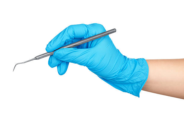Hand in blue glove holding dental tool isolated on white Hand in blue glove holding dental tool isolated on white dental equipment hand stock pictures, royalty-free photos & images