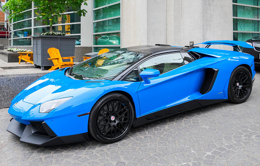 Montreal, Quebec, Canada - May 16, 2015: Parked in front of a hotel, a Lamborghini Aventador LP700-4.  Hotel facade in background with another vehicle slightly visible behind.  The Aventador is the replacement for the Murcielago and contains many visual clues similar to Lamborghini's limited-edition Reventón.