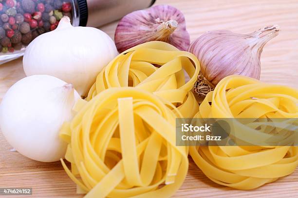Spaghetti Onion Garlic And Pepper On Wooden Plate Stock Photo - Download Image Now