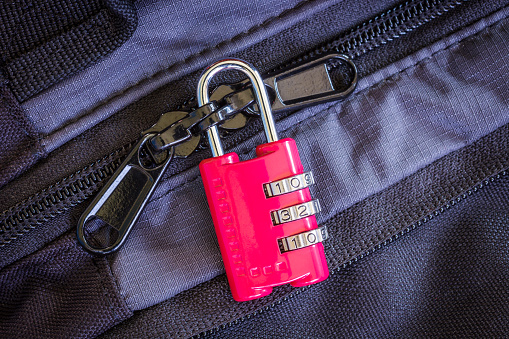 A little red combination padlock locking zippers on luggage