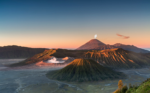 Early morning view of the Bromo caldeira in East Java in Indonesia. The volcanic formation of a few volcanoes, with the famous volcano Bromo and the Semeru volcano in the background attract everyday large crowds of visitors on the mountain top for sunrise.