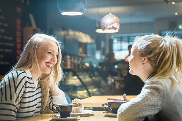 istock Two young beautiful women laughing and having coffee in cafe 474625792