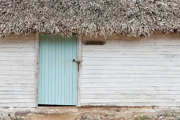 house front of an white wooden cottage in valle de viñales / cuba. light turquoise wooden door.