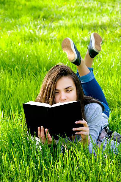 istock beautiful young woman reading a book in park 474631724