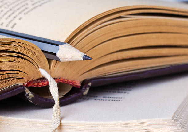 istock Close-up view of grey wood pencil lying on opened book 474640532
