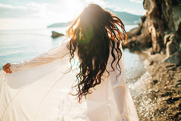 viento en el pelo de ensueño chica con sunflare en la playa - cabello castaño fotografías e imágenes de stock