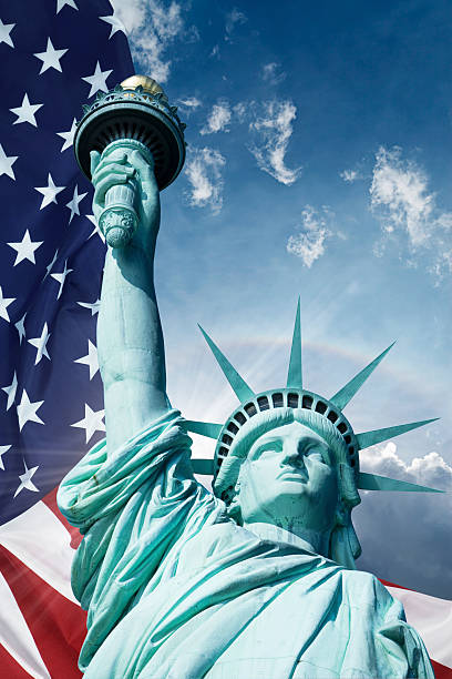 Statue Of Liberty And American Flag Under Blue Sky stock photo
