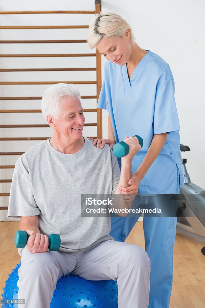 Senior man training with his therapist Senior man training with his therapist in fitness studio  20-29 Years Stock Photo