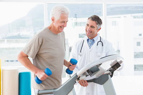 Senior man on treadmill with therapist  Senior man on treadmill with therapist in fitness studio  treadmill stock pictures, royalty-free photos & images