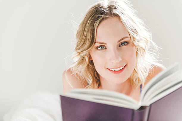 istock Woman indoors in bed reading a book 474647860