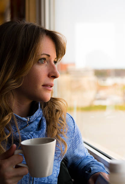 istock Young Woman Drinking Coffee by a Window 474648936