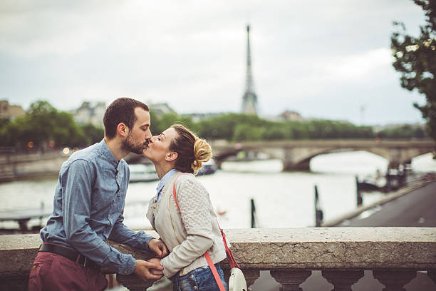 Loving couple in Paris Young loving couple is kissing in Paris, France, on one of it's famous bridges, while Eiffel tower is in the background. paris france eiffel tower love kissing stock pictures, royalty-free photos & images