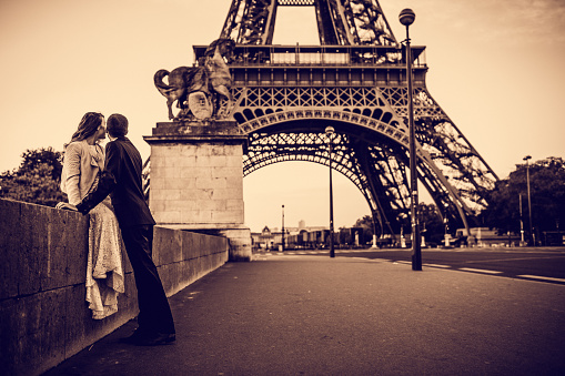 Young couple looking together on Eiffel Tower in Paris, France - on their first morning as married couple