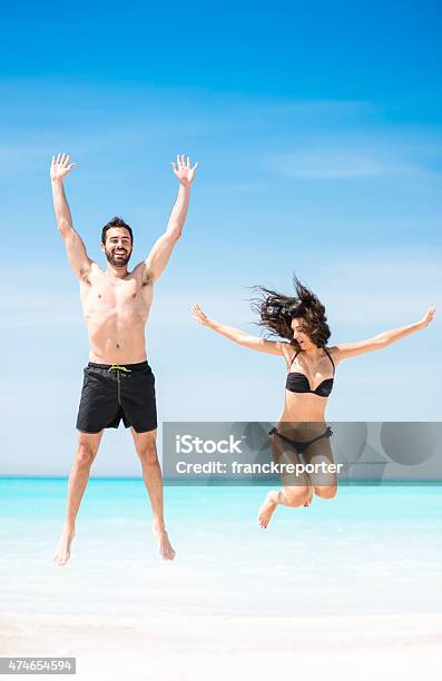 Happiness Couple At The Seaside Jumping On The Beach Stock Photo - Download Image Now