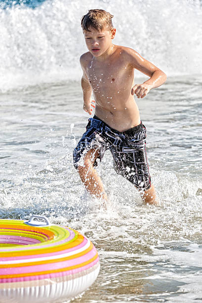 istock Boy Enjoys a Day in the Surf Chasing His Innertube 474665240