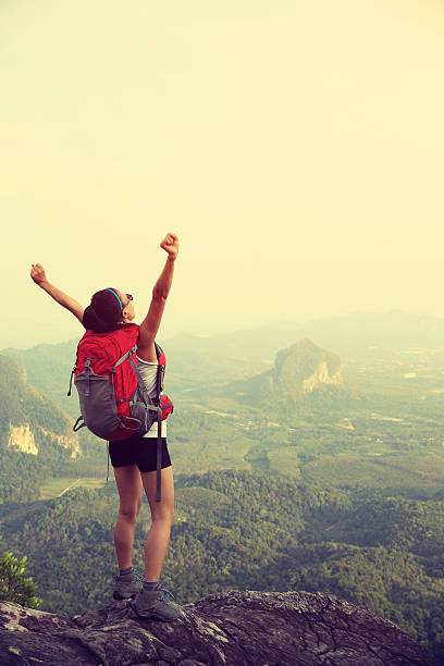 istock cheering woman hiker open arms at mountain peak 474676034