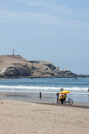 Barranca, Peru - January 22, 2015: Male Peruvian beach trader with his mobile ice cream stall ibn tricycle on Barranca Beach on the Pacific Coast to the north of Lima