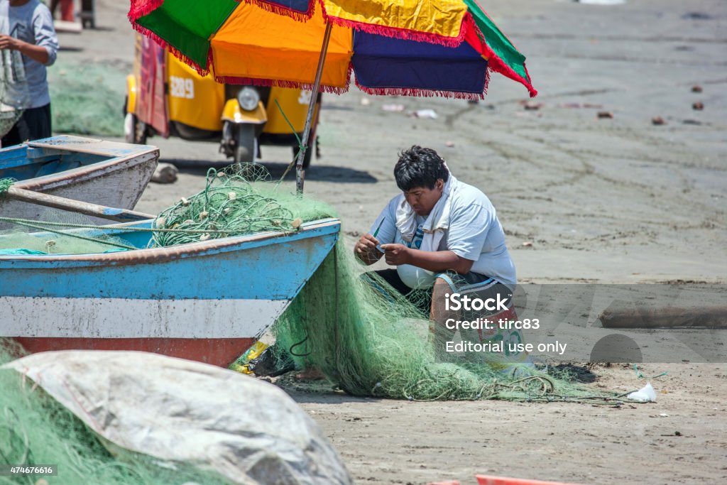 Fishermen working on their boats and nets Barranca, Peru - January 22, 2015: Fishermen working on their boats and nets on Barranca Beach to the north of Lima in Peru Peru Stock Photo