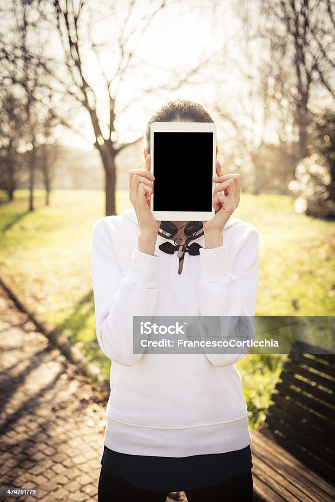 Woman using digital tablet at the park Young italian woman smiling and using her digital tablet at the park with blank screen. Adult Stock Photo